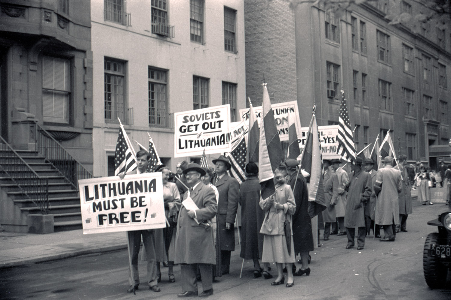 1953 – New York, USA. A group from the Lithuanian American community protests against the Molotov-Ribbentrop Pact and the occupation/annexation of Lithuania, at the Loyalty Day parade. They carry 14 Lithuanian and 14 US flags. In the first row, Kęstutis Trimakas, a member of the Lithuanian National Union of Students (LSS), hold a poster. LVCA, photographer: G. Penikas.